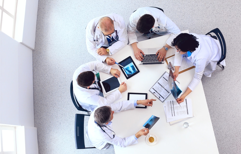 Medical team sitting and discussing at table, top view.